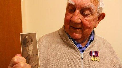 John Stout with a photo of him in wartime uniform
