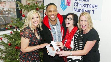 Military Wives choir members Sam Stevenson, Nicky Kenyon and Kerry Riva are pictured receiving their Official Singles Chart Number 1 Award by Reggie Yates