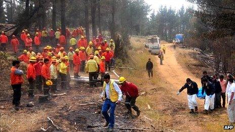 Chilean firefighters look on as police recover the body of a dead colleague