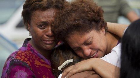 Relatives of a family killed by a mudslide hug outside the church during the wake of the victims in Jamapara, Rio de Janeiro state, Brazil, on 10 January