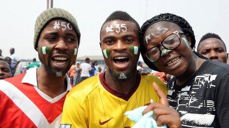 People with their faces painted with the national green and white colours, and different naira denominations on their forehead, pose during a Lagos demonstration