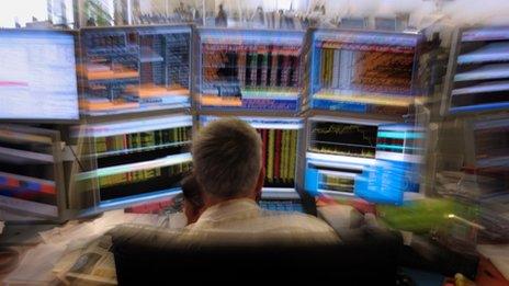 Stock market trader on the phone in front of screens