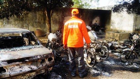 A rescue worker inspects burnt-out wreckage in the Marhaba area of Kano, on January 21
