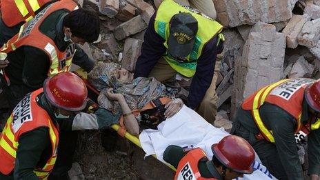 Injured woman carried from rubble of factory in Lahore