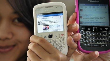Indonesian girls with Facebook on their mobile phones