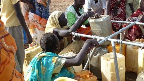 Women fill bottles at a refugee camp but water is scarce