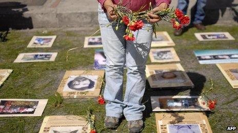 Human rights activists place flowers next to the portraits of people who disappeared during the armed conflict in Guatemala, on 24 February 2012 in Guatemala City