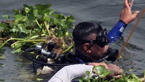 A rescue worker in scuba diving gear recovers the body of a drowned passenger