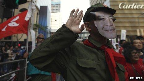Protester wears a mask depicting CY Leung at a demonstration in Hong Kong on 1 April 2012