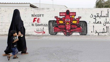 A woman and boy walk past graffiti urging the boycott of the 2012 Bahrain Grand Prix (18 April 2012)