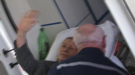 Yulia Tymoshenko waves from a stretcher as she is moved to an ambulance in Kharkiv, 22 April