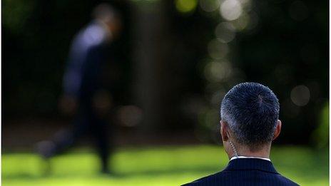 Secret Service agent watches as President Barack Obama walks in the White House grounds, 27 April 2012