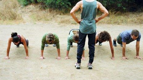 People do push-ups behind an instructor