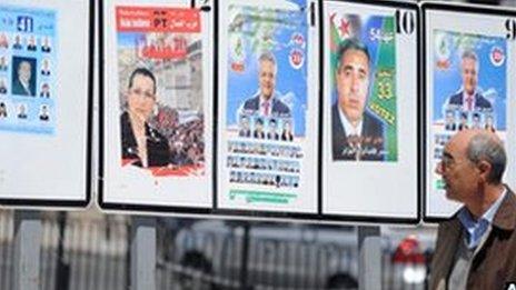 A man walks past candidates' election posters in Algiers
