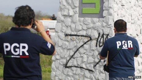 Federal agents take photographs of a Z sprayed onto a wall near a crime scene in Cadeyreta