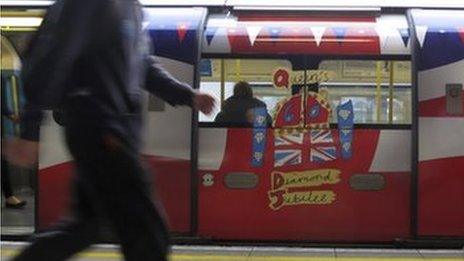 People walk along a platform at Stratford station past a tube train painted to celebrate Britain's Queen Elizabeth II Diamond Jubilee