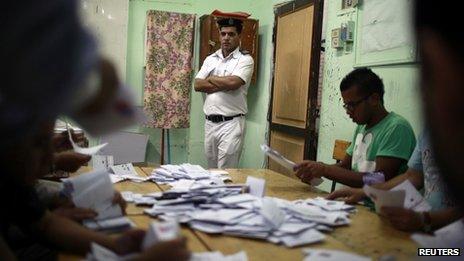 An Egyptian policeman watches as officials counting the vote after they polls are closed in Cairo May 24, 2012.