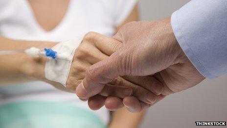 Man holding a patient's hand (with drip)