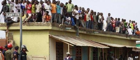 People stand on top of a house viewing the site of a plane crash in Lagos, Nigeria, Monday 4 June 2012