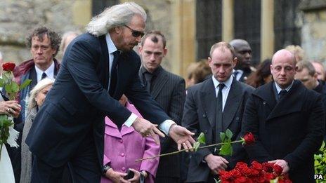 Barry Gibb releases a rose onto his brother"s grave