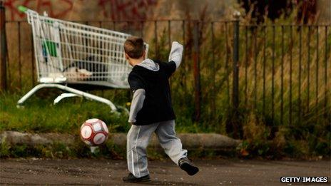 Child playing football near shopping trolley