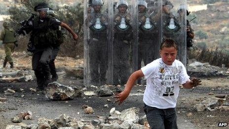 A Palestinian boy runs away from Israeli soldiers during protest against Israel near the West Bank city of Ramallah in 22 June 2012
