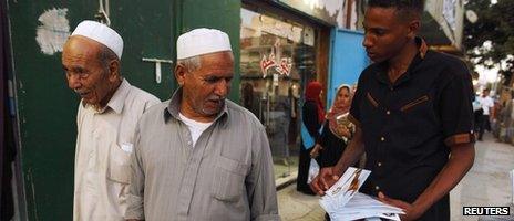 A member of the Justice and Construction Party, the political arm of the Libyan Muslim Brotherhood, hands out brochures of his party candidates to people during their election campaign in a suburb of Tripoli, 4 July 2012