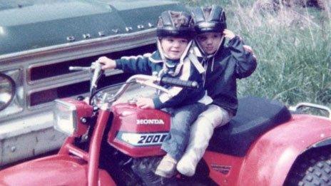 Steven and Chris on a quad bike, wearing helmets