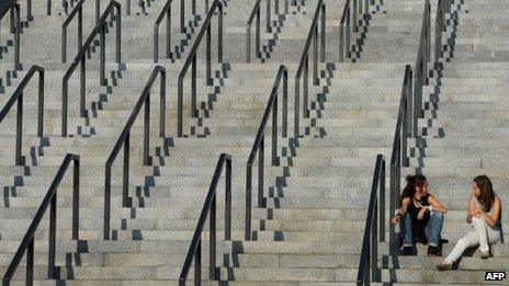 Two young women sit on the steps of the Olympic stadium