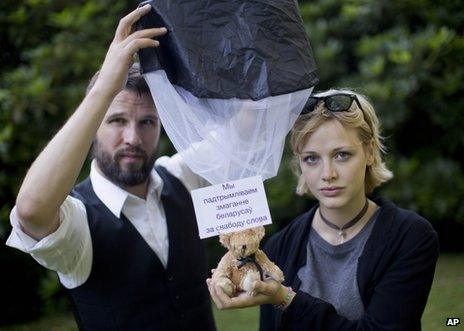 Swedish citizens Tomas Mazetti (left) and Hannah Frey show a teddy bear on a parachute as they pose for a photo in Berlin, 1 August