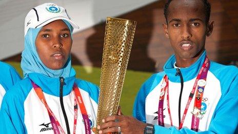 Somali athletes Mohamed Hassan Mohamed (R) and Zamzam Mohamed Farah pose for pictures with a London 2012 Olympic Torch during a visit to to the Foreign and Commonwealth Office in London, on 10 August 2012