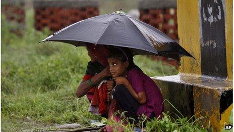 Women protect themselves with an umbrella from monsoon showers at Bharatpur in Rajasthan state, India