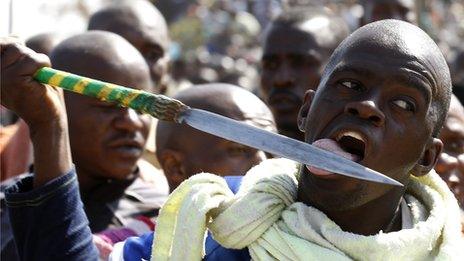 A protester licks his spear at the Lonmin-owned mine in South Africa (16 August 2012)