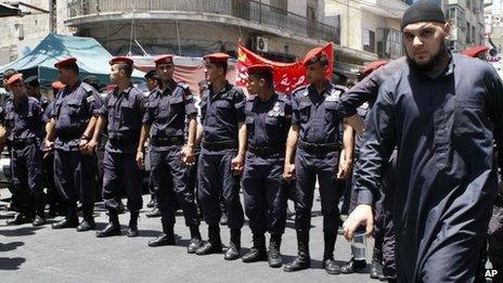 Muslim Brotherhood follower passes riot police in Amman (13 July 2012)