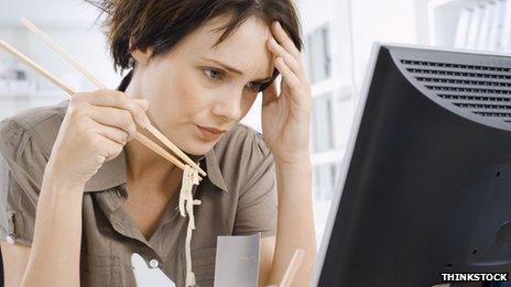 Woman eating noodles at her desk