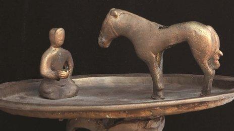 Raised bronze trays featuring a figure kneeling in front of a horse at the Smithsonian Freer and Sackler Asian Art galleries