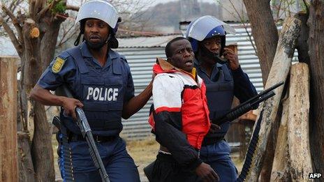 South African police arrest a miner as part of a crackdown in Marikana on Saturday