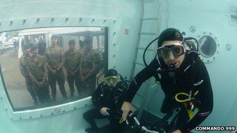 Marines watch Chris Sirett and Brian Stokes through a window as they attempt the underwater challenge