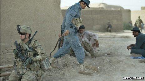 A NATO soldier works with a member of the Afghan National Police