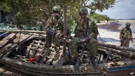 In this Wednesday, Dec. 14, 2011 file photo, Kenyan army soldiers sit on a currently unused fishing boat on the white sand shore of the seaside town of Bur Garbo, Somalia.