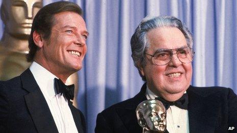 Albert "Cubby" Broccoli, producer of the "James Bond" series, holds the Thalberg Award he received for his work at the Academy Awards, in Los Angeles. Roger Moore, left, British actor who plays secret agent 007 James Bond, made the presentation.
