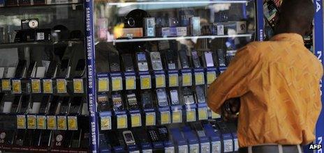 A man stands in front of a shop window displaying mobile phones on 1 October 2012 in Nairobi, Kenya