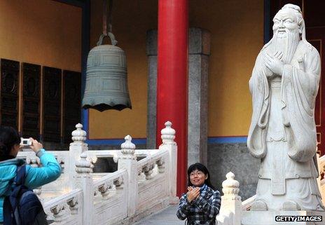 Woman mirroring the pose of Confucius outside the Confucius temple