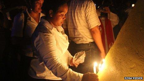 Woman lights candle during events commemorating the 75th anniversary of the massacre