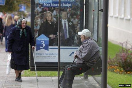 Elderly people at a bus stop with an election poster in Vilnius, 2 October