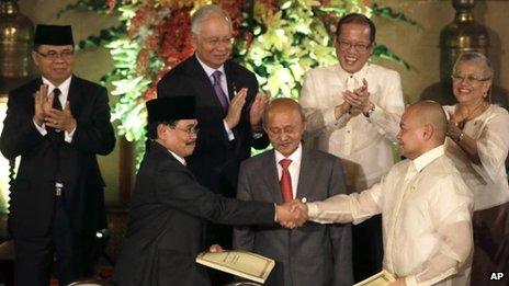 Government peace negotiator Marvic Leonen, right, and Moro Islamic Liberation Front chief negotiator Mohagher Iqbal, left, shake hands as they exchange signed peace documents following formal signing ceremony 15 October, 2012 at Malacanang Palace in Manila
