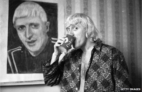 Jimmy Savile poses by a portrait of himself, painted by a friend, in 1965