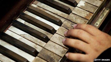A woman's hands at the keyboard of an old piano