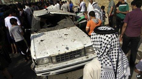 People inspect a car damaged by car bombings in Shula, Baghdad (23 October 2012)