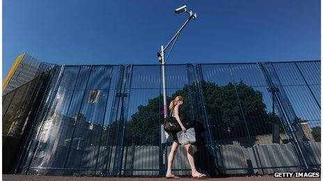 A woman walks past a CCTV camera